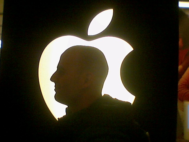 silhouette of man standing in front of computer screen with an apple logo on it