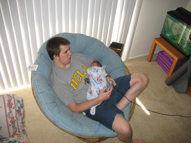 a man is holding a baby in a blue seat