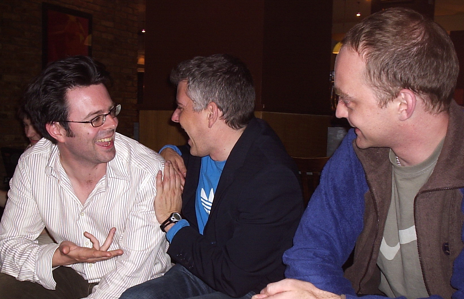 three men sitting on a bench together in the dark