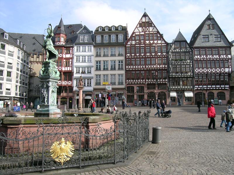 a building with a fountain in front and people walking around