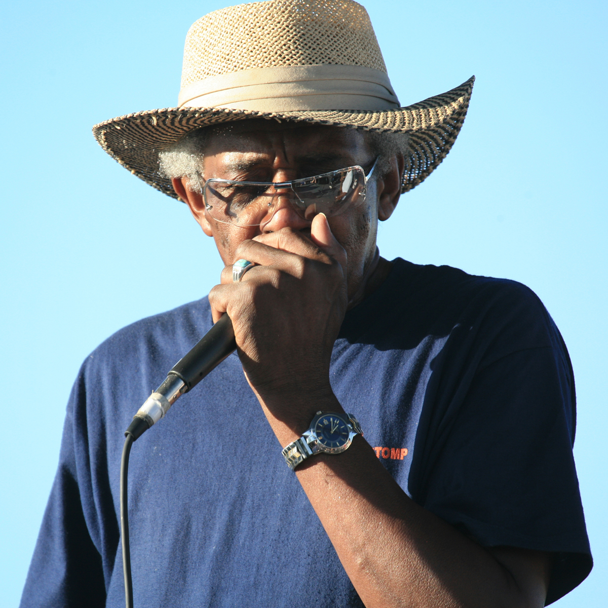 a man is wearing a straw hat and singing into a microphone