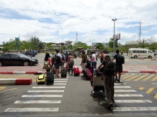 people are standing at an airport waiting for their luggage