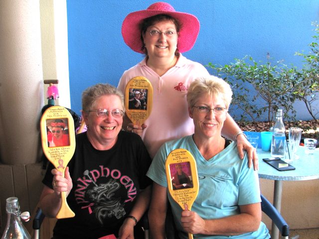 a group of three women holding up yellow paddles