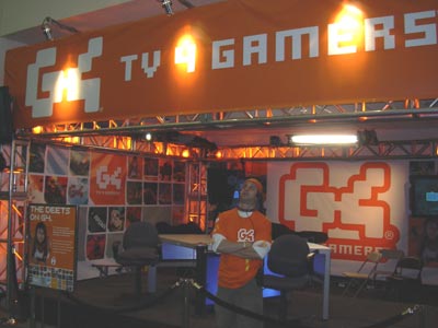 a man standing under a game booth with an orange banner