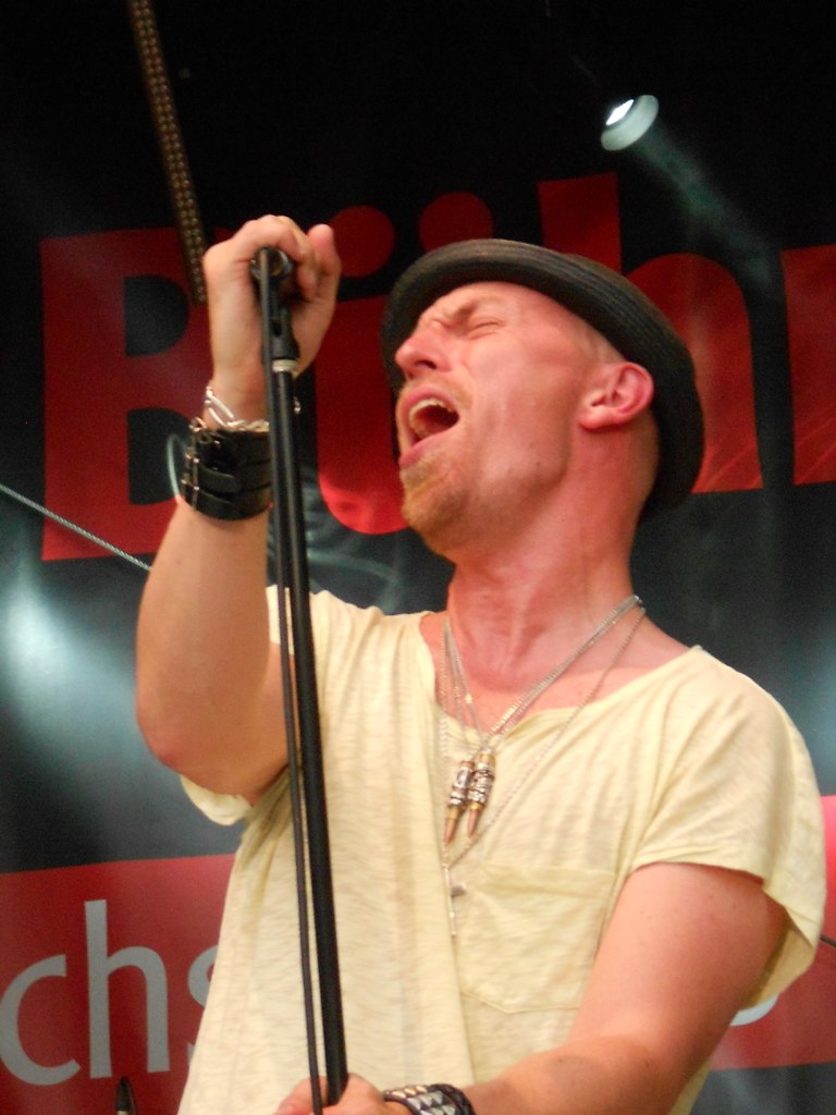 a man in a yellow shirt is singing and holding a microphone