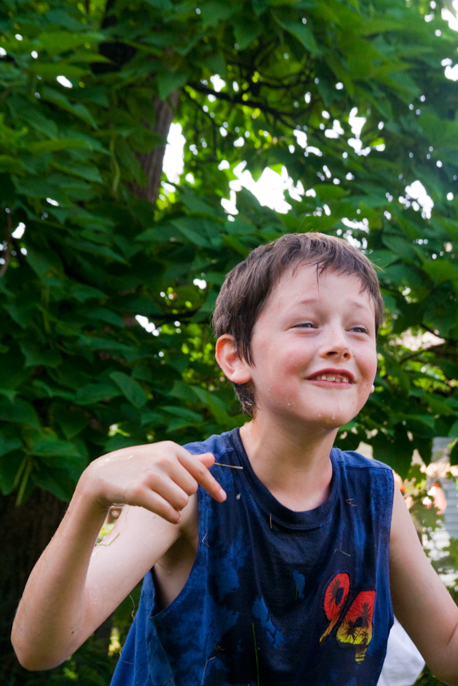 a boy standing outside smiling while holding a frisbee