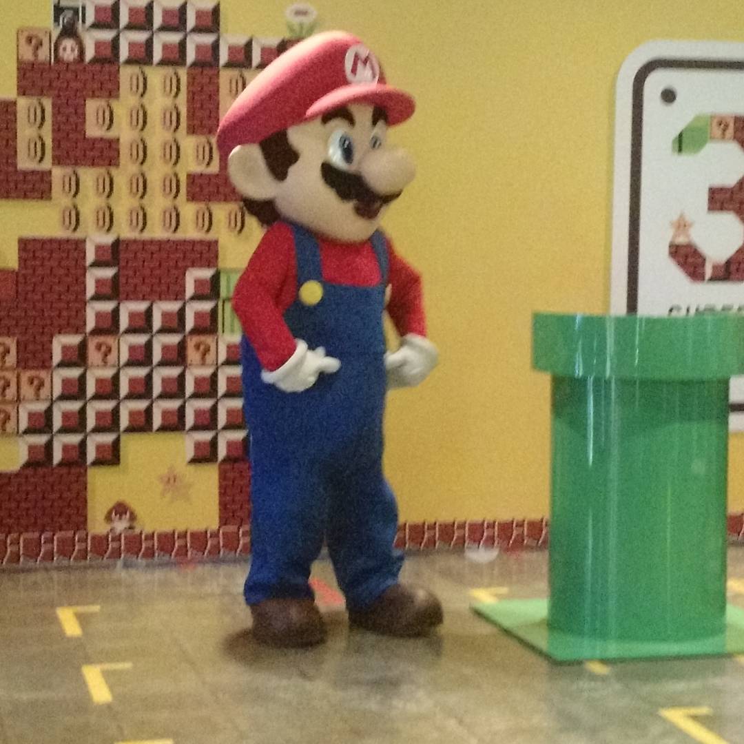 the person is wearing a red cap, blue overalls and an apron