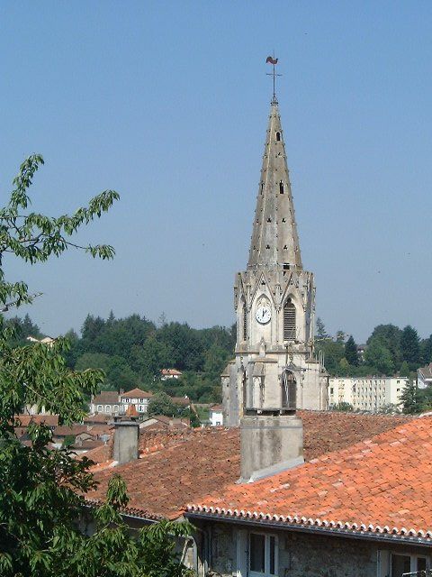 a tall church tower in a city next to houses