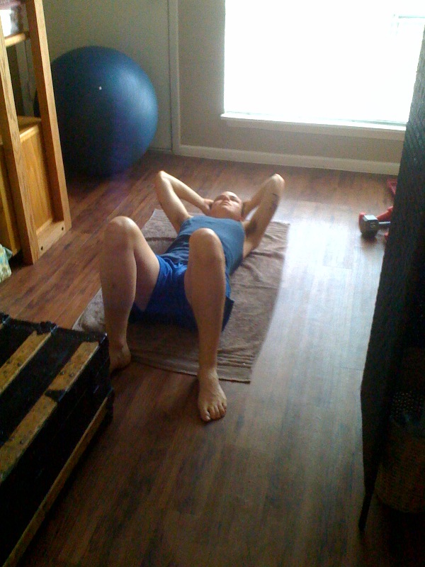 a boy in swim shorts is laying on a yoga mat