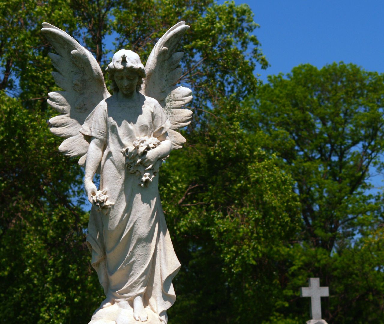 a statue of an angel is in the middle of a cemetery