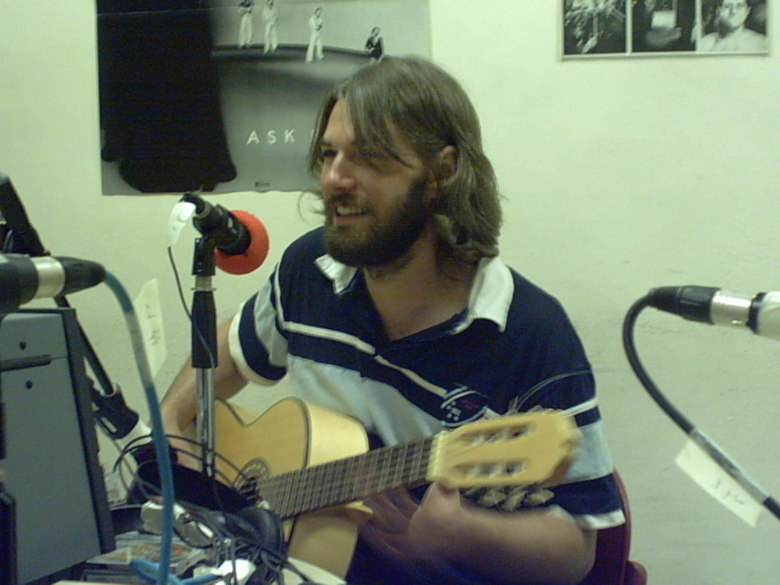 a man sits with his guitar and sings into a microphone