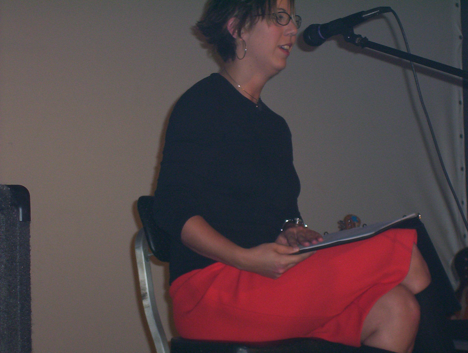 a woman wearing a skirt on stage reading soing