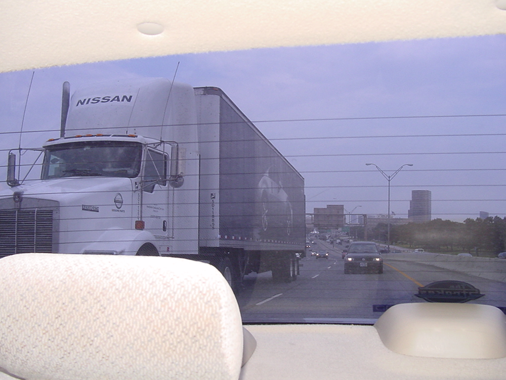 a truck driving on a highway with tall buildings in the background