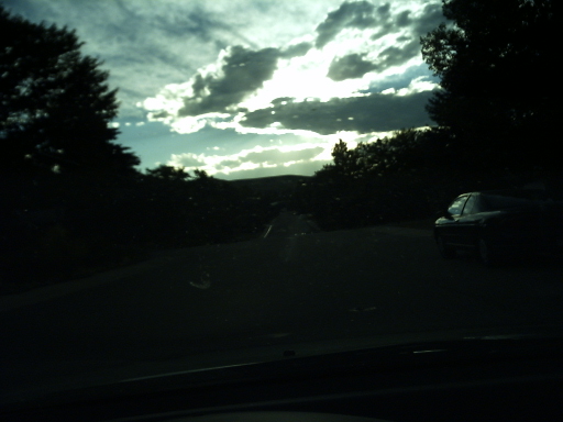 a black car is driving on the road during the sun set