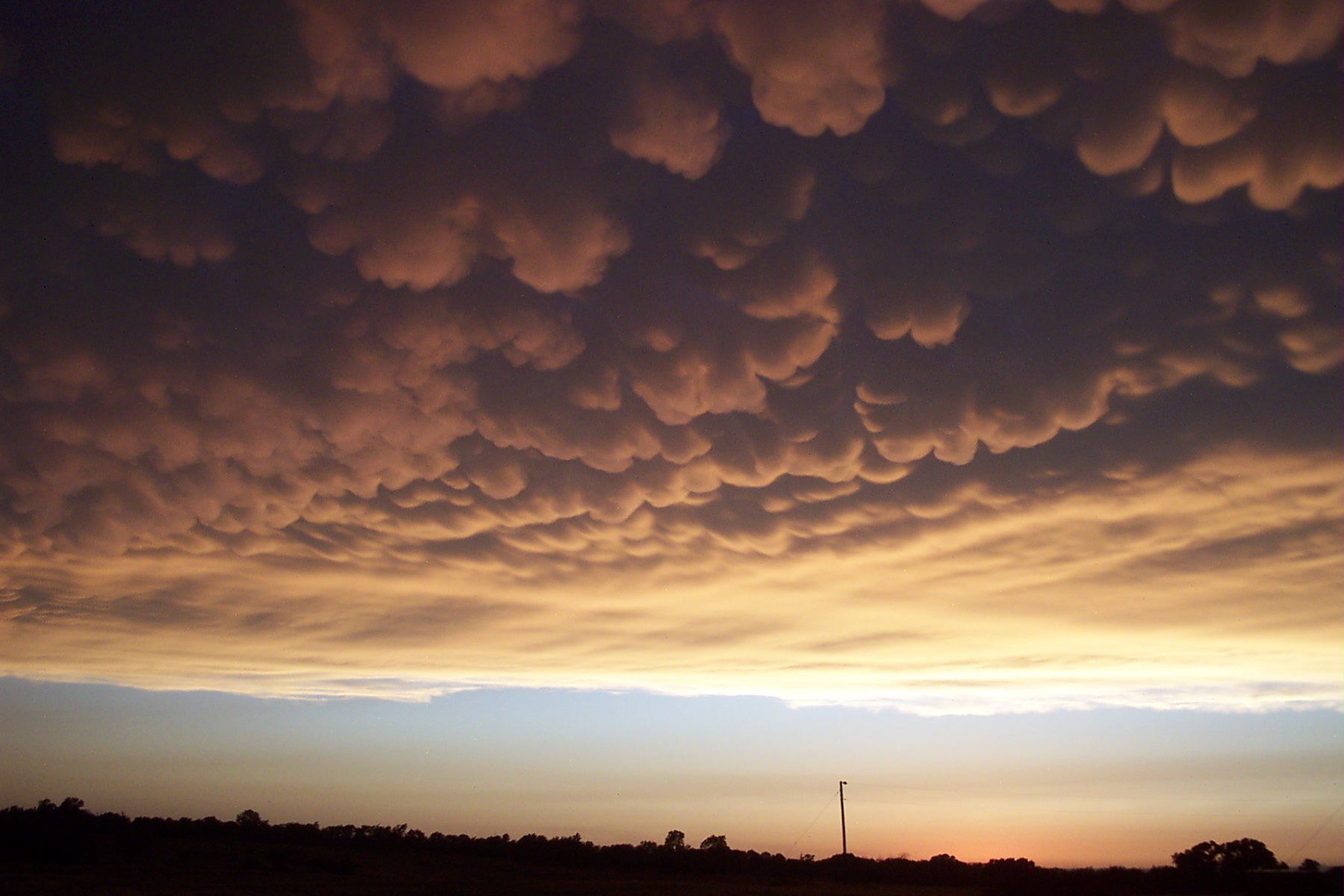 some clouds hanging over a building on a sunset