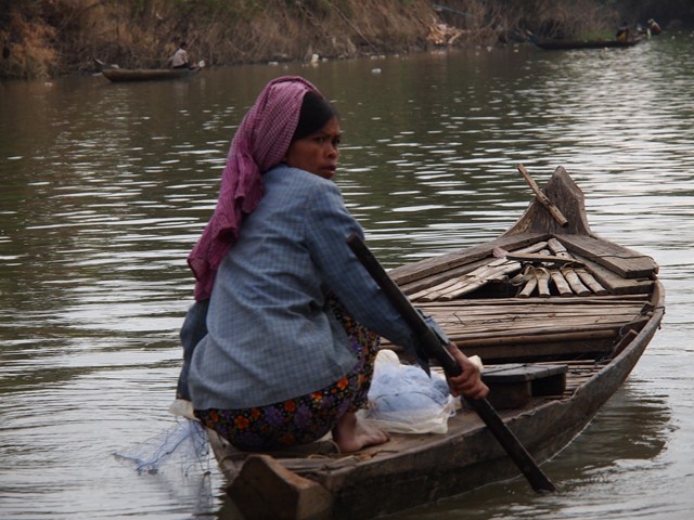 a woman sitting on the end of a boat with a purple scarf around her neck