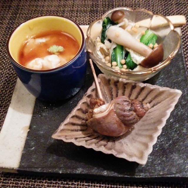 soup, soup, and vegetables sit on a plate near some chopsticks