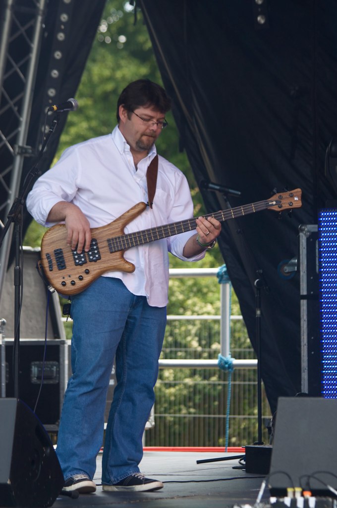 man playing on bass guitar at an outdoor concert