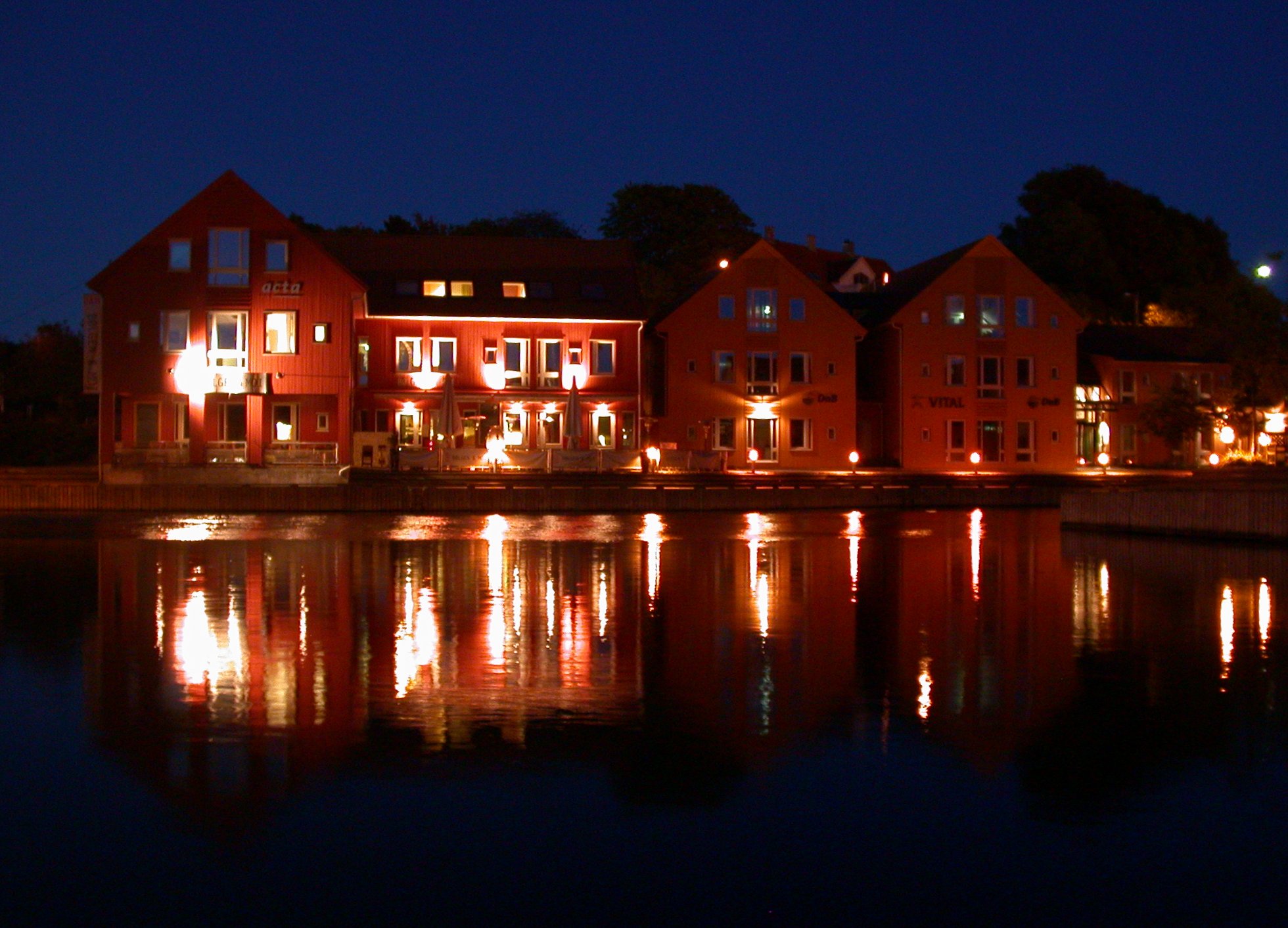 large red building with lit windows is on the water