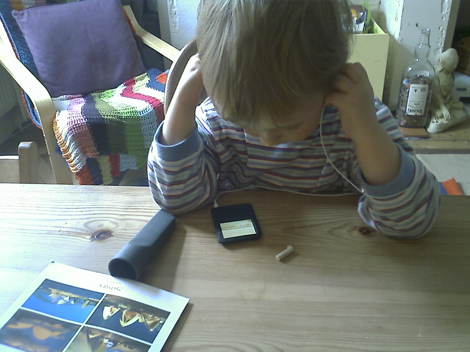 a boy sitting at the table with his head down on his phone and holding his hands in the ear