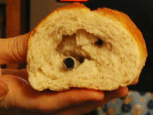 a person holding up a doughnut with a teddy bear in the center