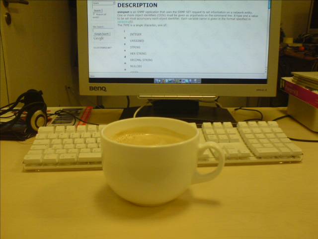 there is a cup of coffee that sits in front of the computer