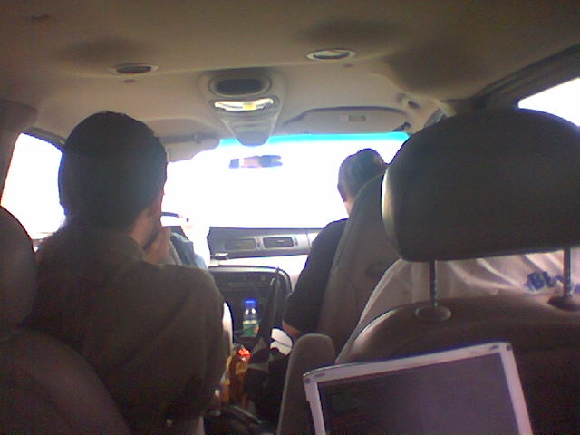 people in the back seat of a car working on a laptop