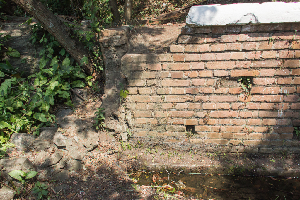 a broken fire hydrant sitting next to a brick wall