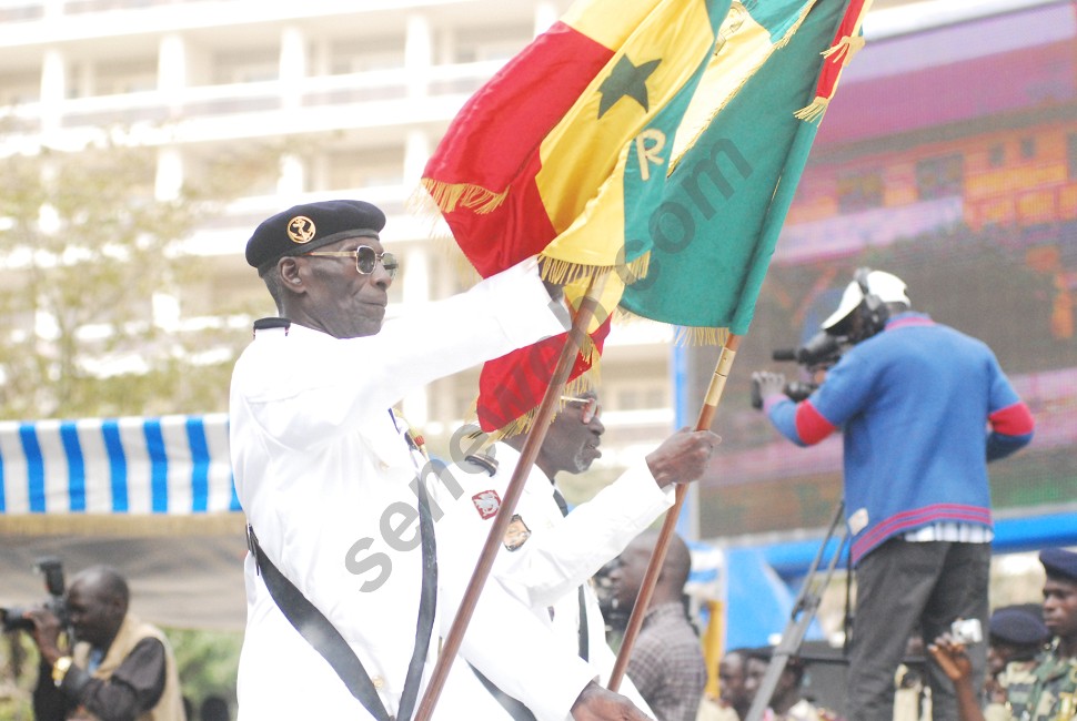 a man wearing military clothing holding two flags and posing for the camera