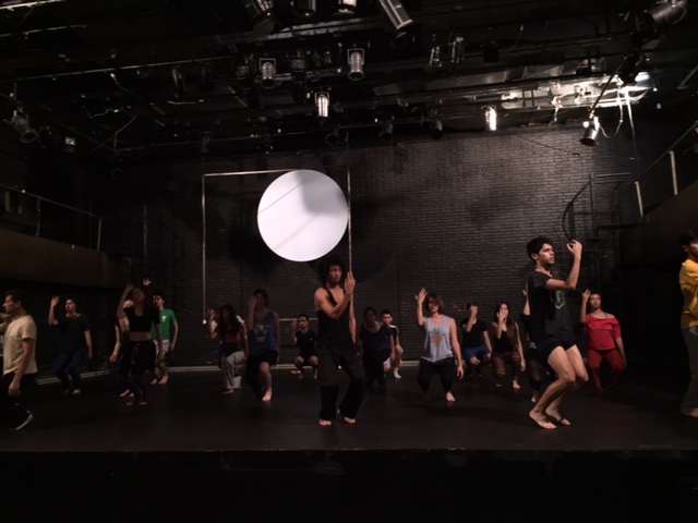 people on stage in a circle doing soing with a white frisbee