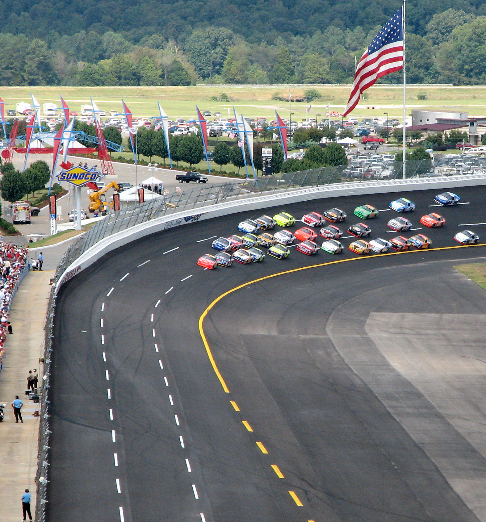some cars are driving down a race track with fans watching