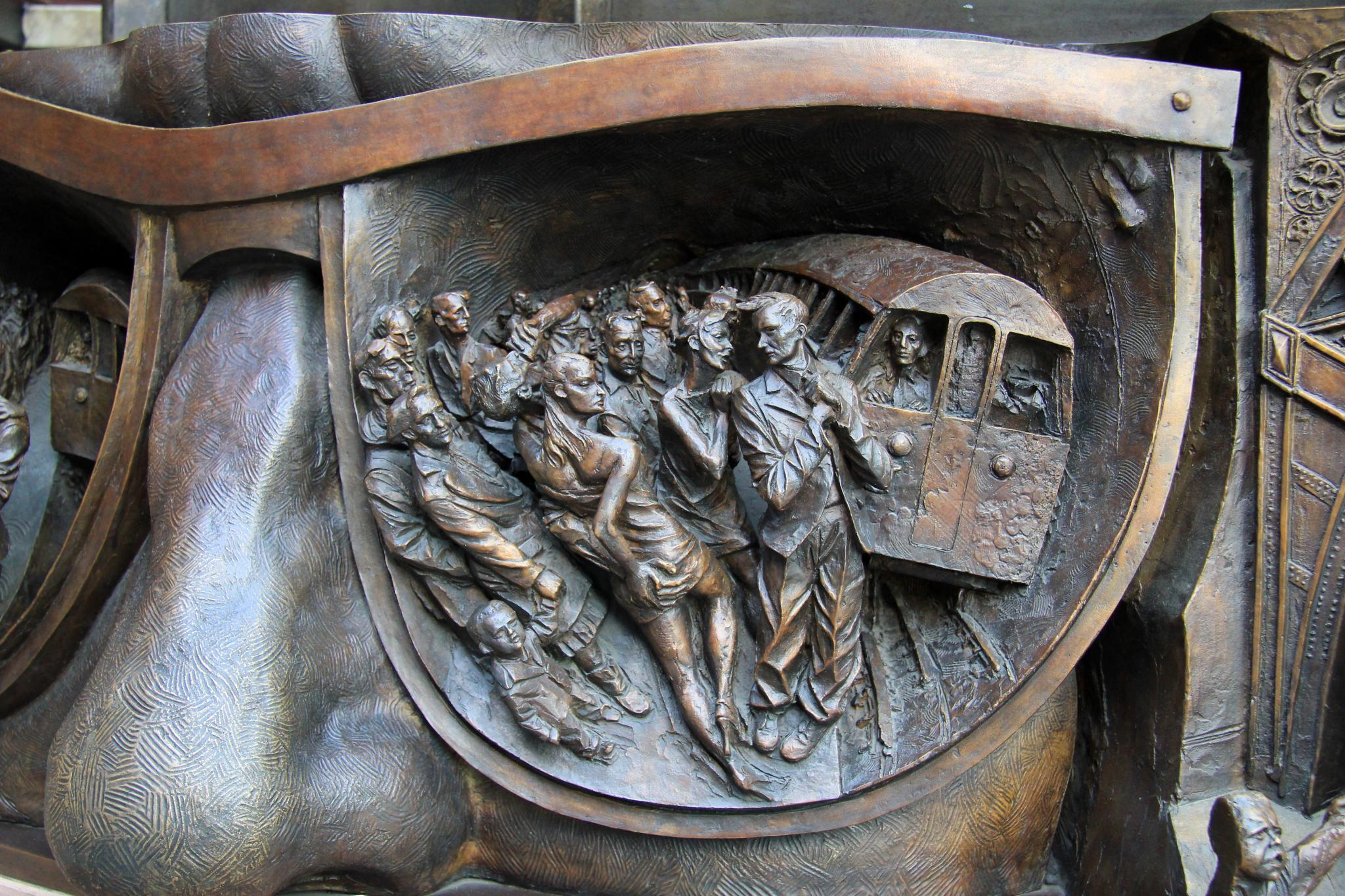 a monument is made of bronze metal, featuring men carrying carts