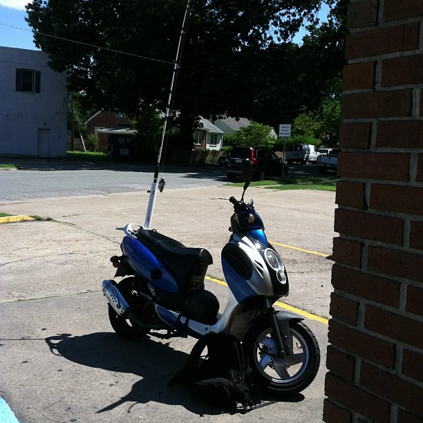 a scooter is parked in a parking lot next to a brick wall