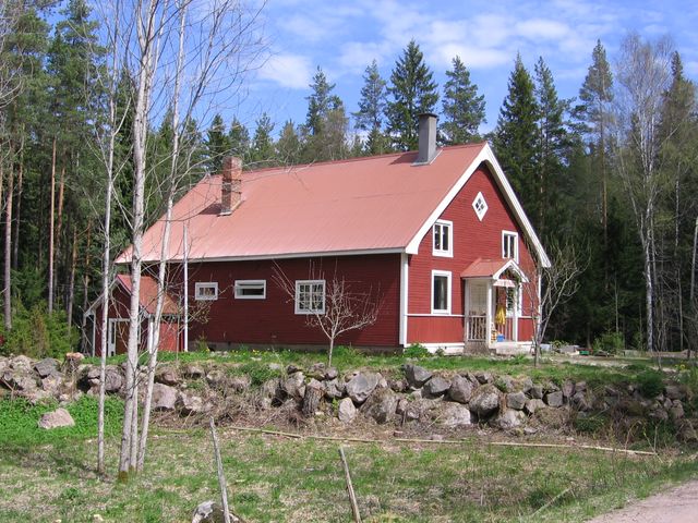 a red farm house surrounded by trees in the country side