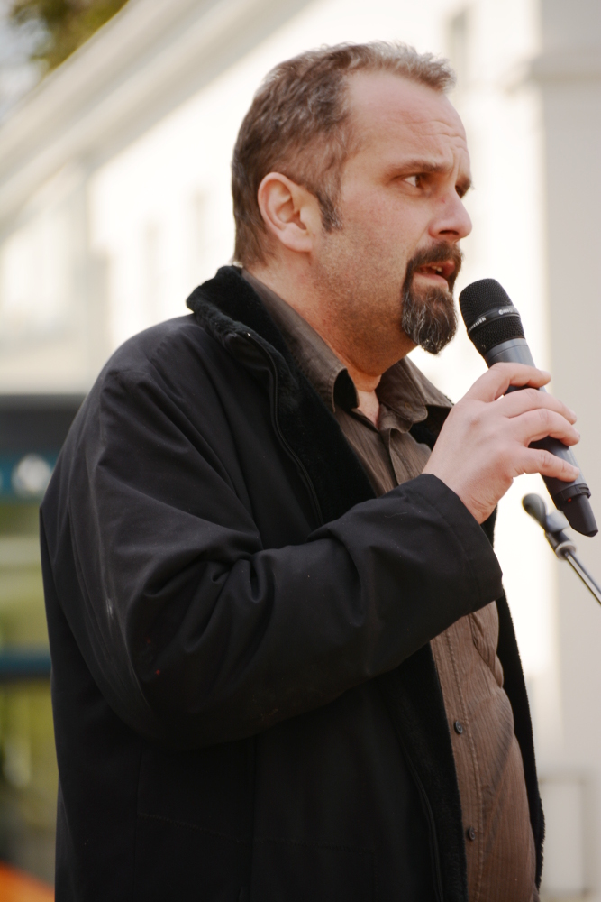 a man with a beard and black jacket speaking