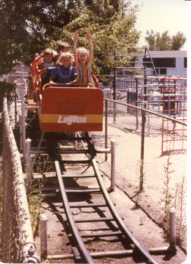 children ride on a roller coaster near a playground