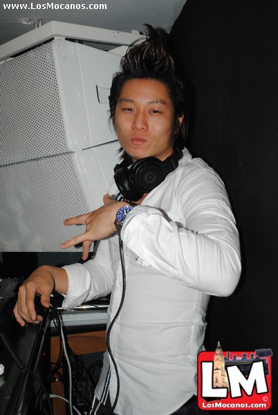 a man in a white shirt holds a dj controller and dj equipment