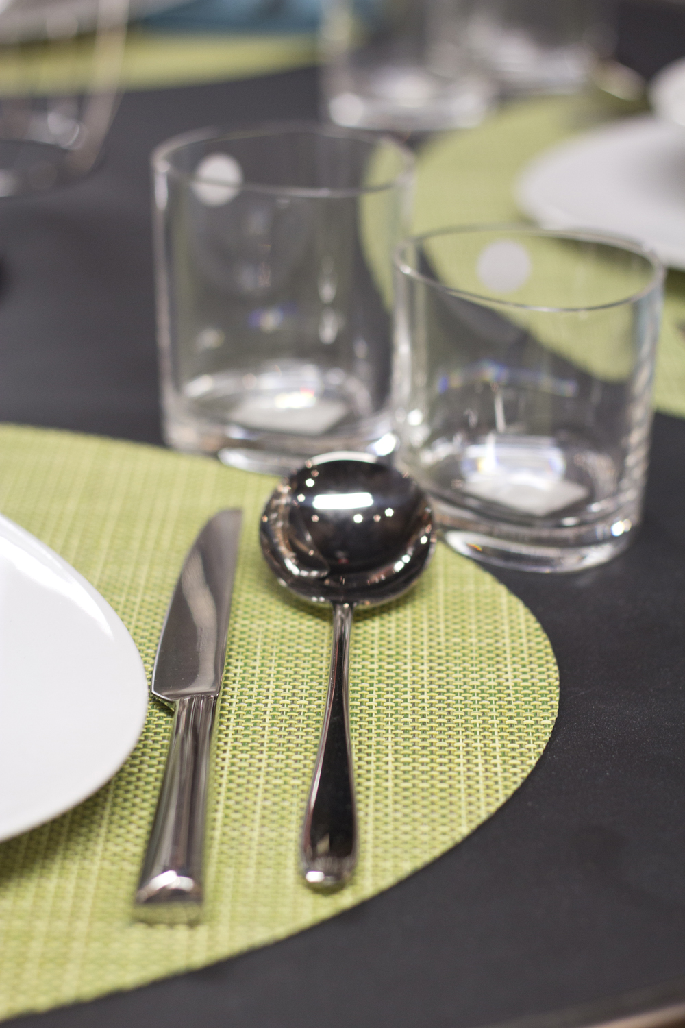 a table with green placemats and glassware