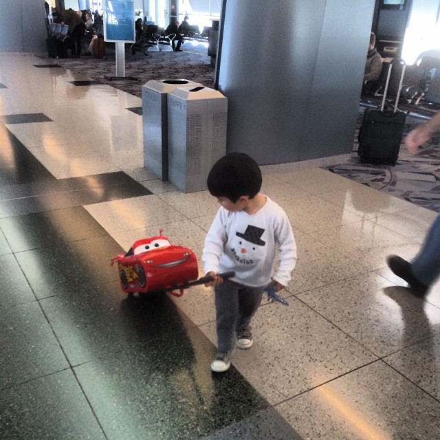 a small child is pulling a cart on a tiled walkway
