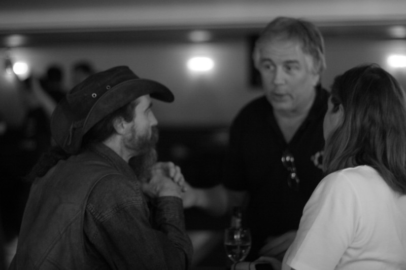 three people sitting around at a table, having drinks