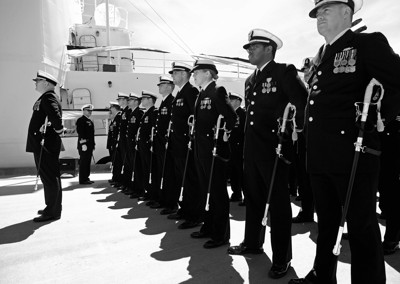 several navy personnel stand in formation with their flags