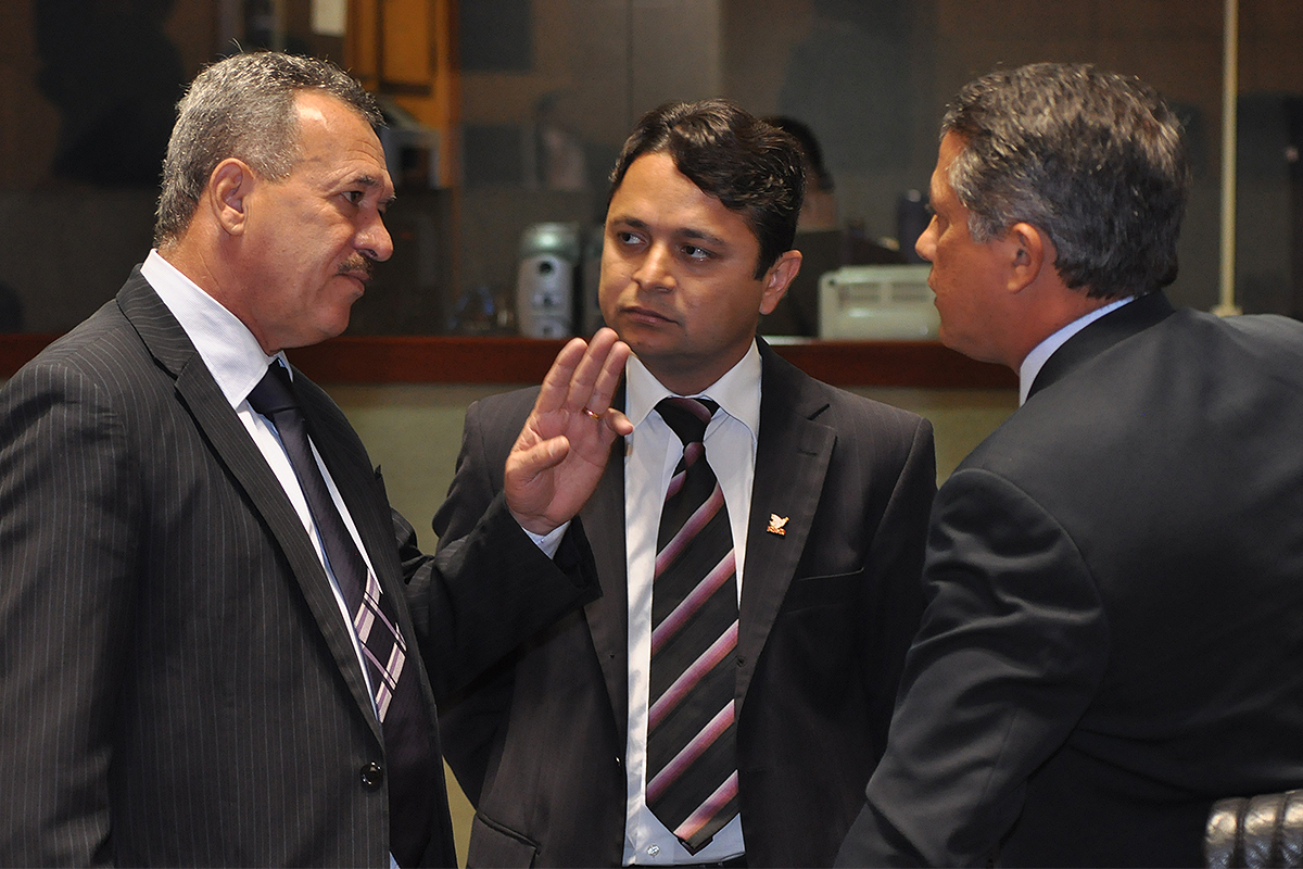 three men are standing together talking and having a conversation