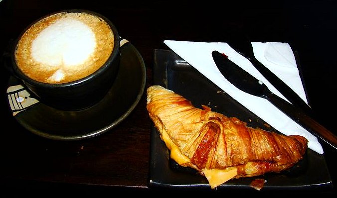 a breakfast dish with a croissant and a beverage in a cup