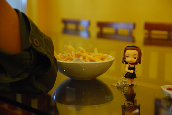 a figurine sitting on a table in front of some french fries