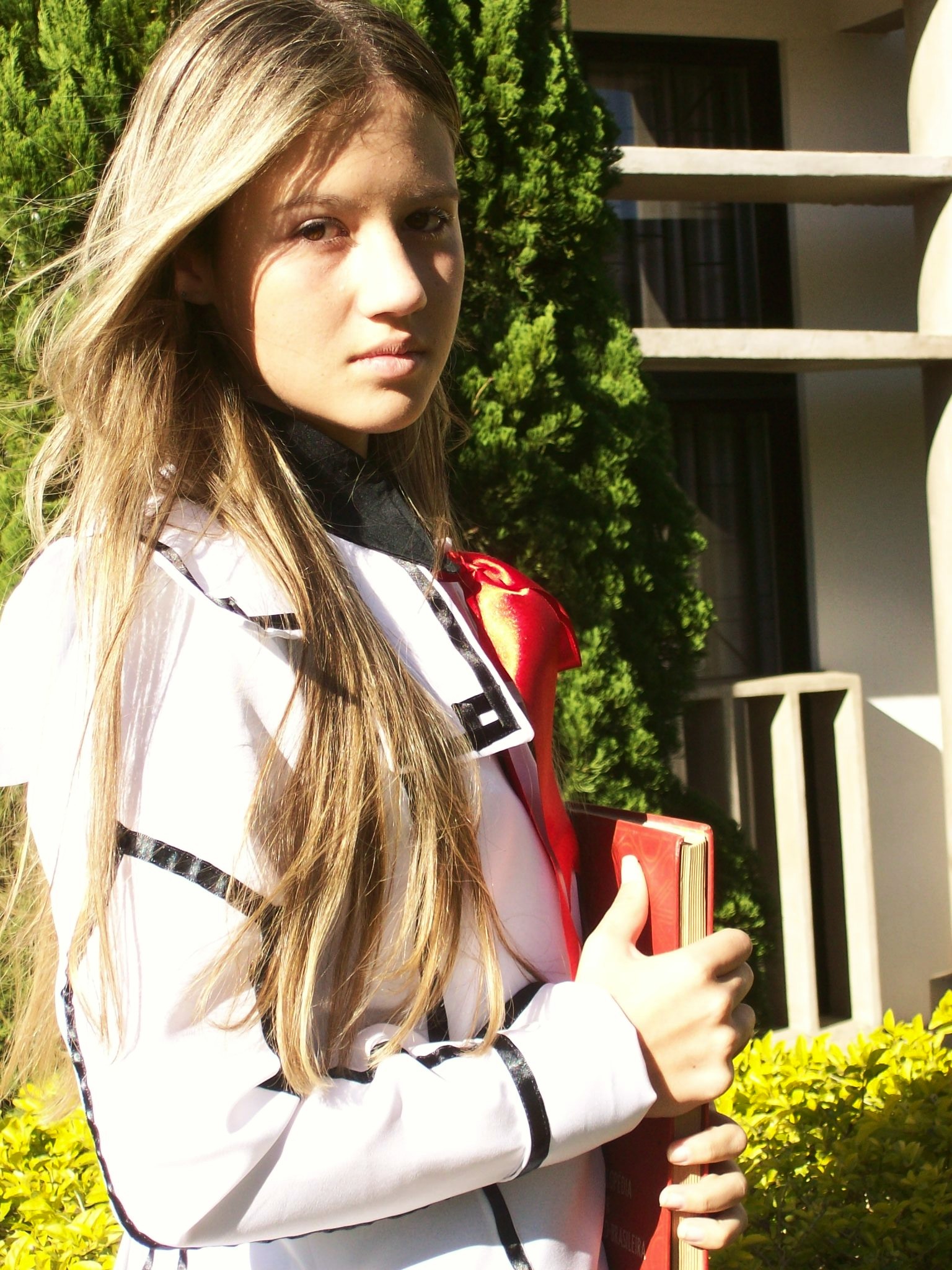 a beautiful young lady holding a red backpack and a purse