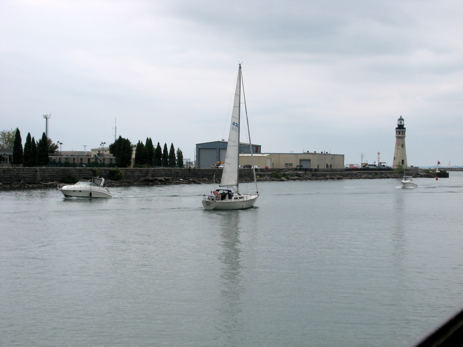 sail boats in the water by a lighthouse