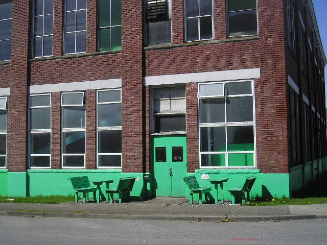green chairs outside a building painted green in the daytime
