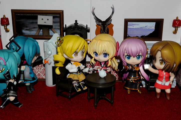 seven chibi action figures displayed on red carpet in living room