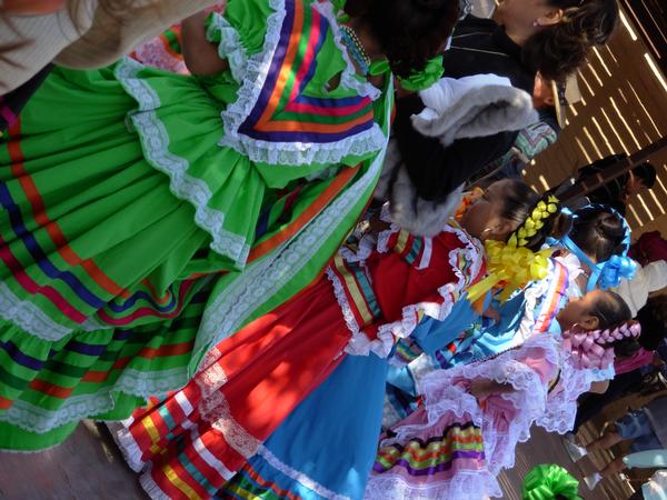 a group of people in colorful dress walking along side of a wall