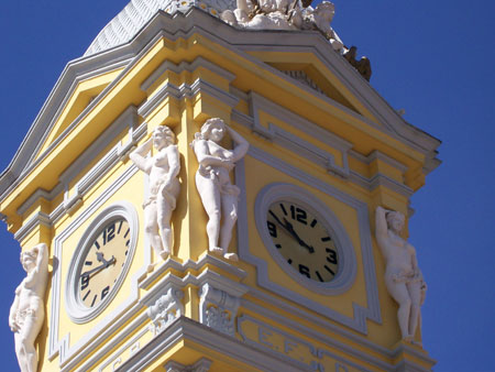 a clock tower with statues at the top and a blue sky in the background
